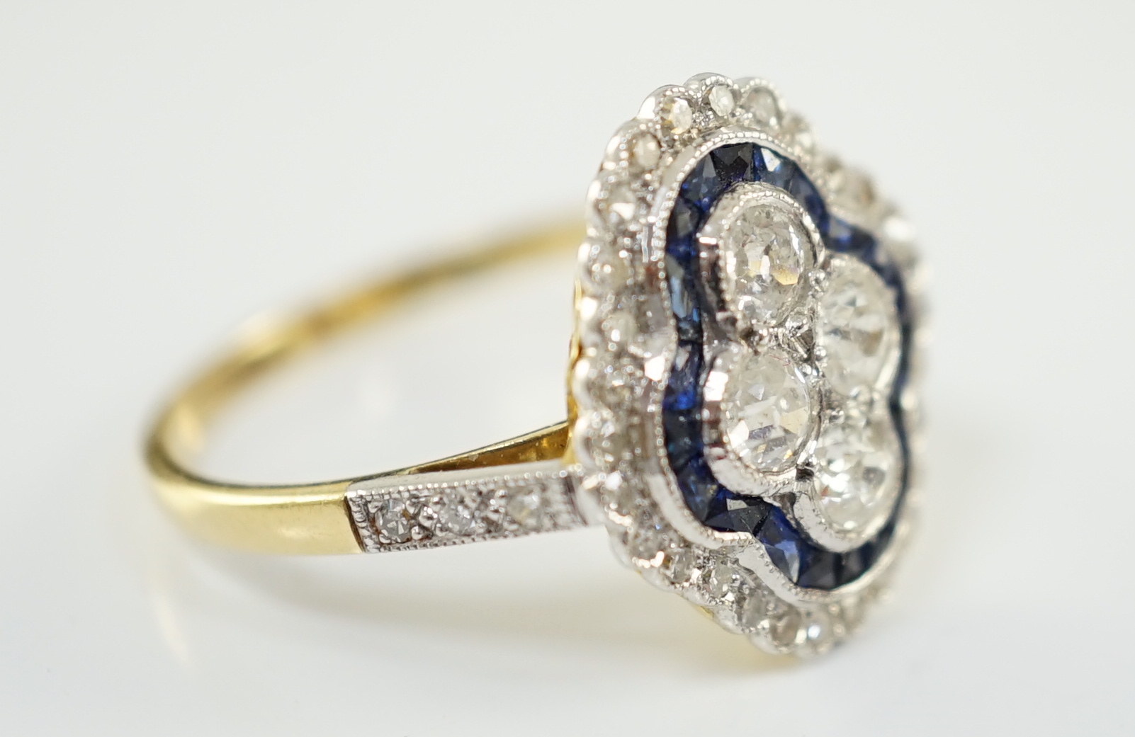 A modern 18ct gold, sapphire and diamond set quatrefoil shaped cluster ring